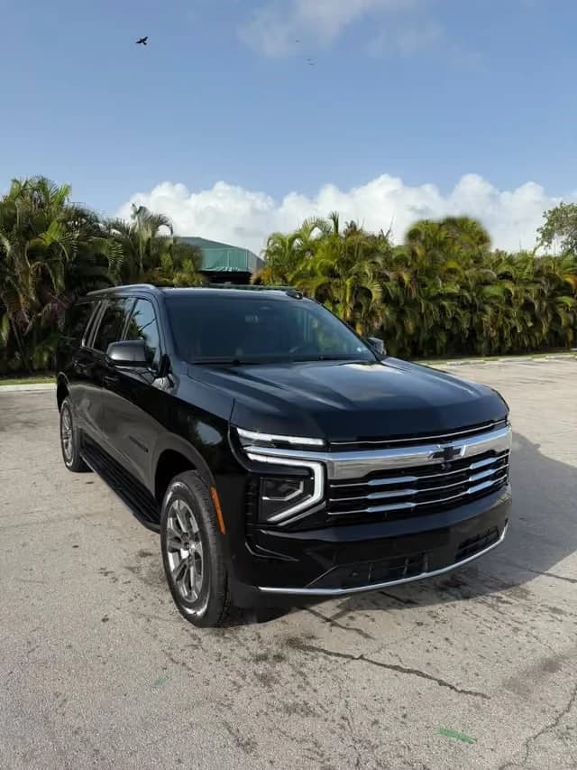 Front of a black Chevrolet Suburban beside palm trees, ready for event transportation in Miami